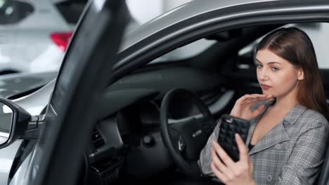 beautiful young woman in a business suit makes a selfie on the phone while sitting in the car