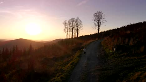 young athletic woman is running outdoor at sunset in mountain landscape.