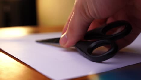 black scissors are placed on a white paper on a wooden table and taken away again