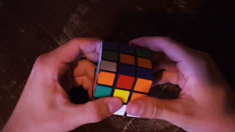 Young-man-trying-to-solve-a-rubics-cube-on-a-wooden-table-4