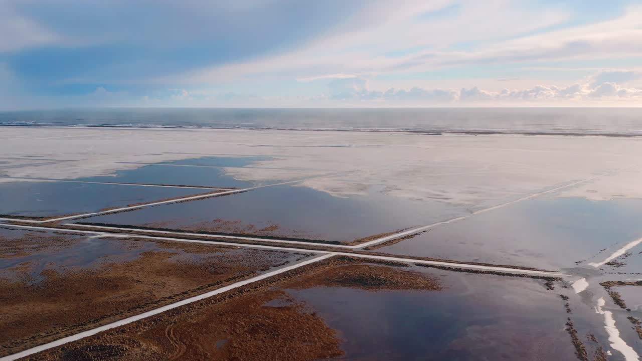 Sobrevoo aéreo do delta de um rio islandês com o Oceano Atlântico ao fundo ao pôr do sol.
