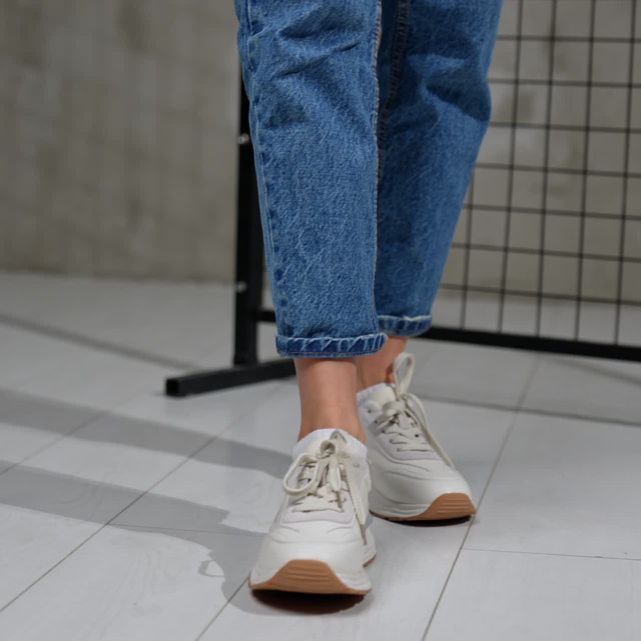 Girl in short blue jeans and light white sneakers. Trendy sport shoes presentation in photo studio