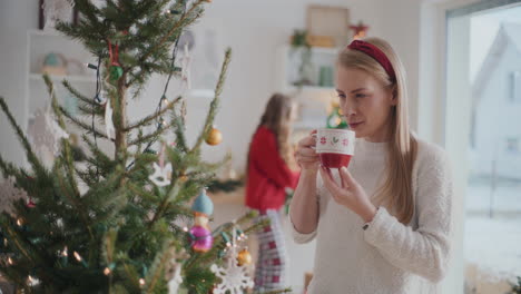 Hermosa-Joven-Sonriendo-Mientras-Toma-Café-Cerca-Del-árbol-De-Navidad