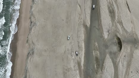 top down drone shot of white suv on jericoacoara beach with atlantic ocean during the day in jijoca de jericoacoara, ceara, brazil