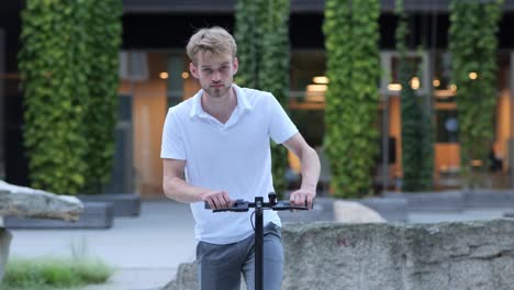 Young-businessman-walks-to-his-e-scooter-and-rides-off,-medium-shot