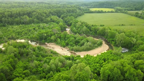 flyaway shot of plush green countryside, revealing a drying river