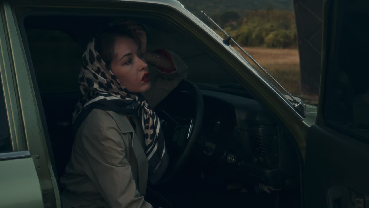 Woman in a vintage car, facing troubles