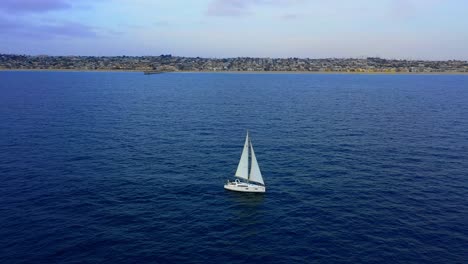 Velero-Blanco-En-Hermosas-Aguas-Azules-Frente-A-La-Costa-Del-Sur-De-California-Vista-Aérea-De-Drones