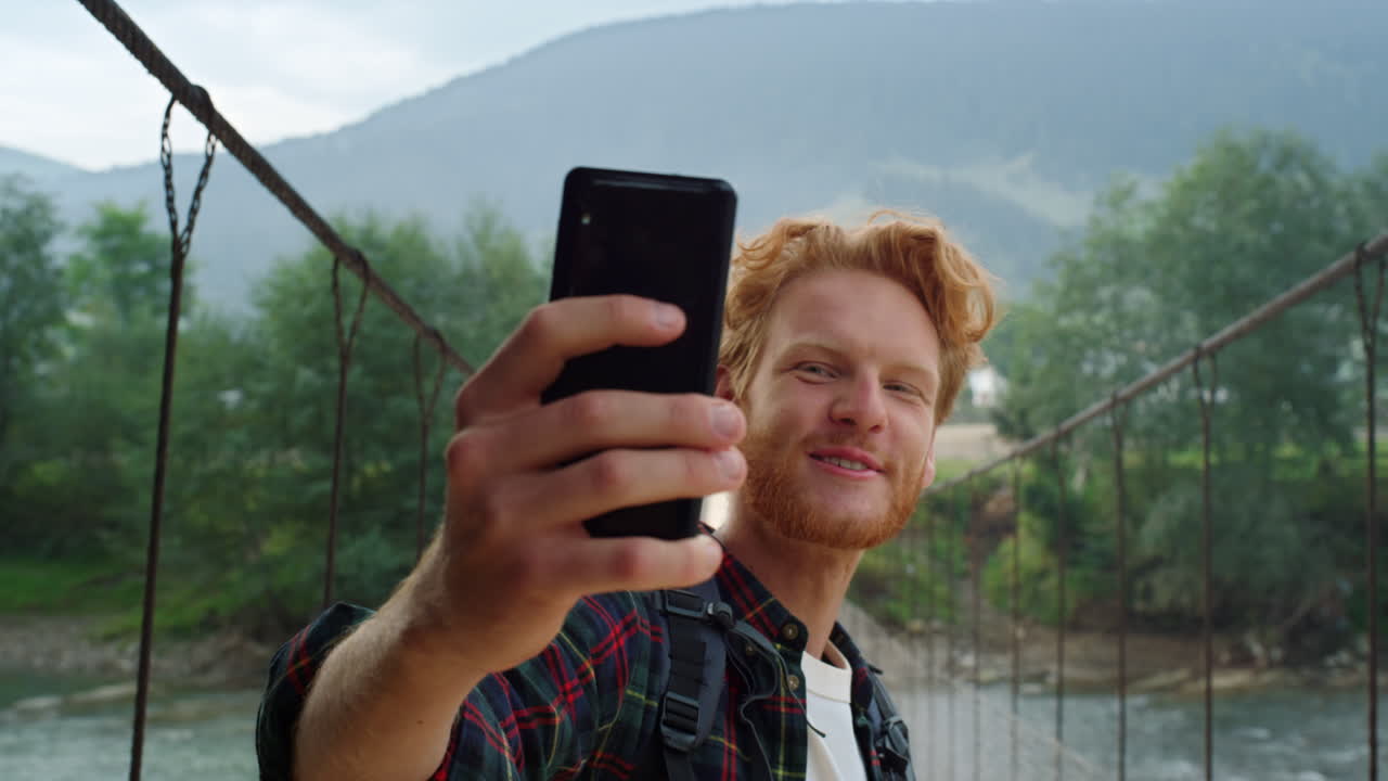 Gros plan sur une touriste qui parle et utilise son smartphone pour un appel vidéo dans les montagnes estivales.