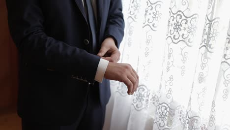 handsome groom fixes his jacket. wedding morning. businessman. slow motion