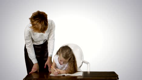 mom helping daughter with homework on white background