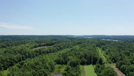 drone flies over green trees, farmland and brown lakes before revealing beautiful potomac river, maryland