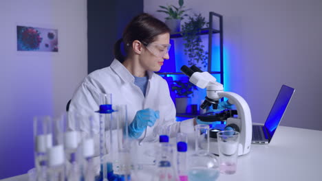 científico trabajando en un laboratorio con un microscopio y una computadora portátil