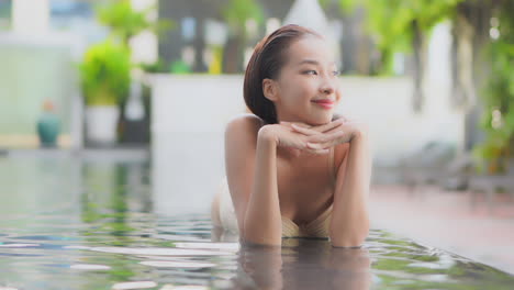 필드의 좁은 깊이 사랑스러운 젊은 여성이 그녀의 왼쪽을 바라보고 리조트 인피니티 풀의 얕은 가장자리에 그녀의 배에 누워