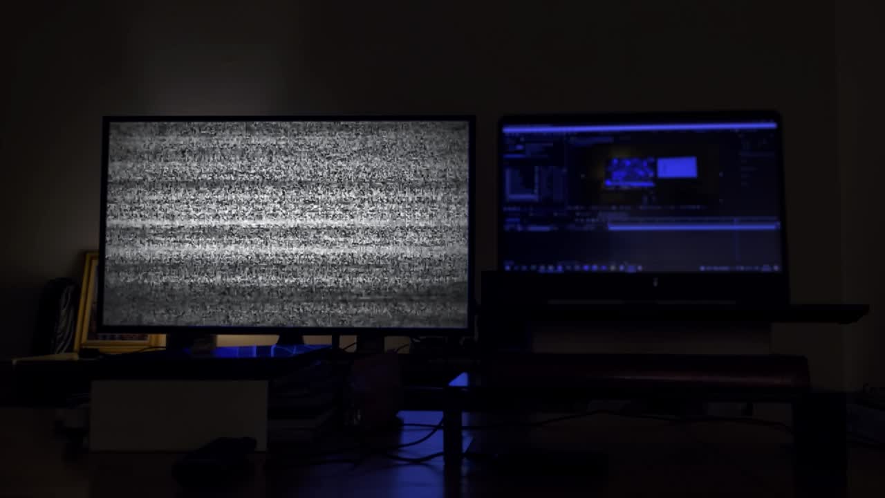 어두운 방 안의 흐릿한 노트북 근처에 초록색 화면을 가진 스마트 tv. 4k 해상도.