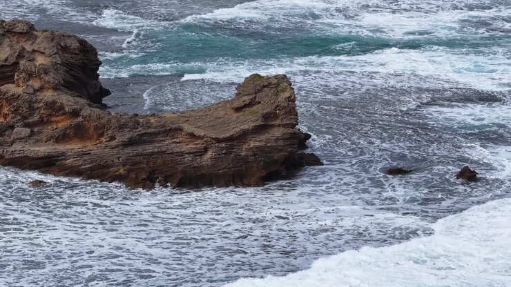 Onde oceaniche si infrangono sulla frastagliata Sphinx Rock, cielo coperto, campo lungo stabile, paesaggio marino spettacolare