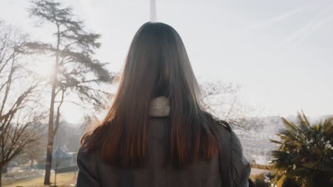 카메라는 행복하고 우아한 여자가 가을 파리를 따라 걸어가는 것을 따라갑니다. 유명한 에펠탑을 향해 비즈니스 여행에서 느린 동작으로.