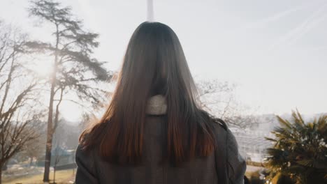 camera follows happy elegant woman walking along autumn paris towards famous eiffel tower on business trip slow motion.