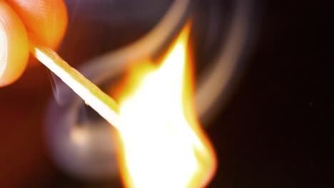 hd super slow motion cinematic macro shot of a match being lit, in a dark room