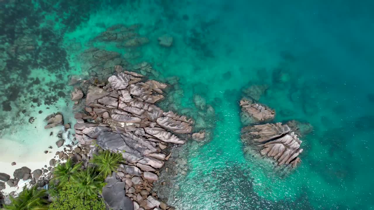 Veduta aerea ascendente della spiaggia delle Seychelles con rocce, massi e acqua turchese