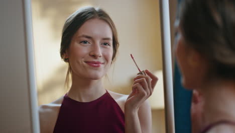 gorgeous girl applying lipstick in mirror reflection closeup. joyful model enjoy