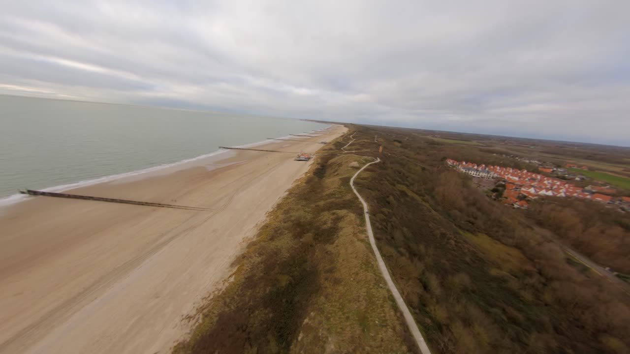 Fast aerial shot of the beach and the dunes, going from low to high angle