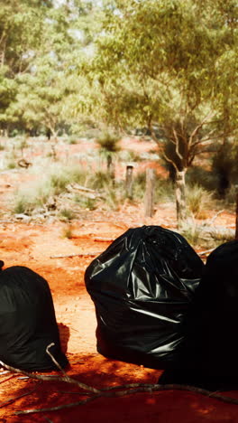 bolsas de basura negras sentadas en la tierra roja en el interior de australia.