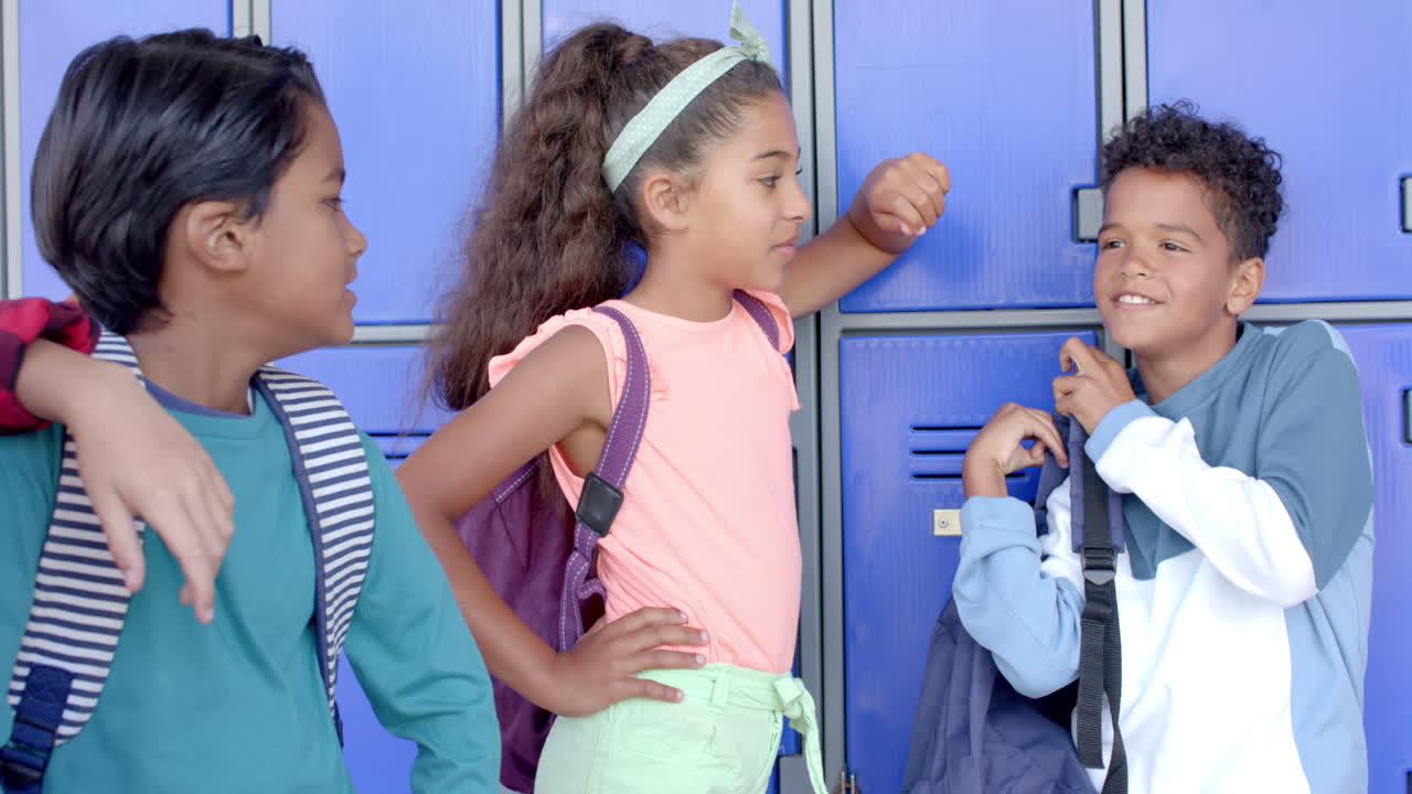 Three students by blue background lockers in school hallway