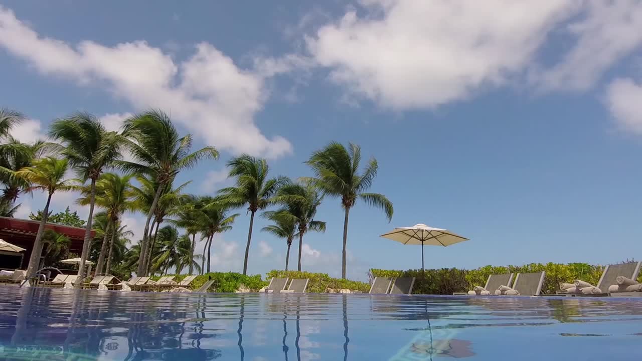 olas de piscina, cielo azul, nubes blancas y palmeras