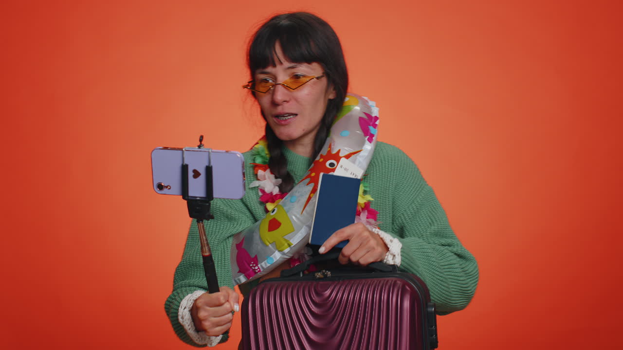 Traveler blogger woman in sunglasses with luggage taking selfie on smartphone record make video call
