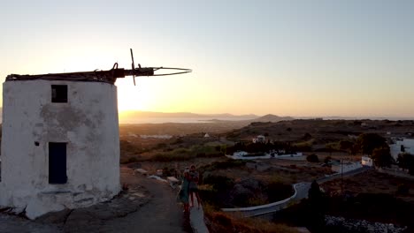 aerial of couple enjoying naxos sunset in vivlos village windmills, greece