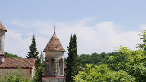 Motsameta-monastery-church-steeples-with-crosses-above-trees,-Georgia