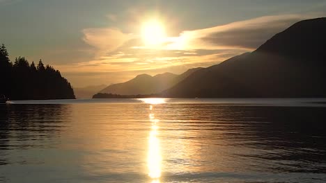 Orange-sunset-with-mountains-clouds-water-skier-in-background