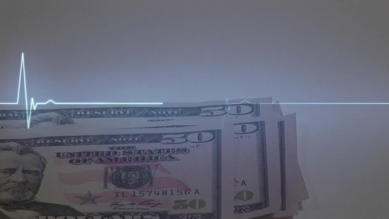 테이블 위에 미국 달러 지폐를 놓고 있는 사람의 심장 박동 모니터의 애니메이션.