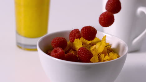 frambuesas vertiendo en un tazón de cereales en la mesa del desayuno