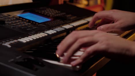 Close up shot with the hands of a man playing an electronic keyboard, piano music, candle light, by the fire