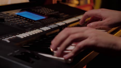 close up shot with the hands of a man playing an electronic keyboard, piano music, candle light, by the fire