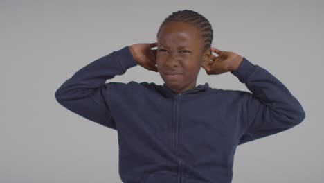 studio shot of boy on asd spectrum showing sensitivity to loud noises or sounds wearing ear defenders 3