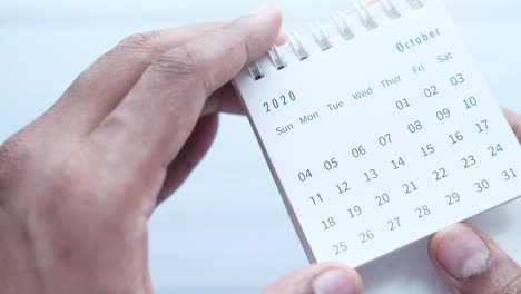 las manos sosteniendo un calendario de octubre de 2020