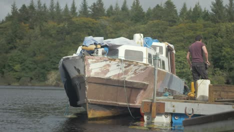 a young man wiping down faired hull of motor cruiser before painting