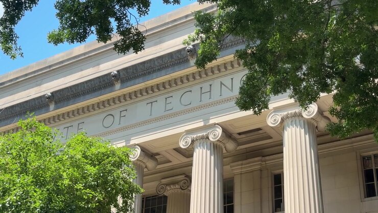 Primo piano della facciata del Massachusetts Institute of Technology con colonne classiche e rami d'albero che incorniciano l'edificio.