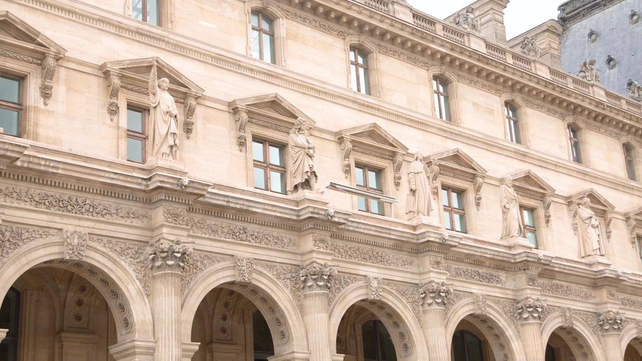 Um zoom lento revela as intrincadas esculturas em pedra e estátuas da fachada do Louvre.