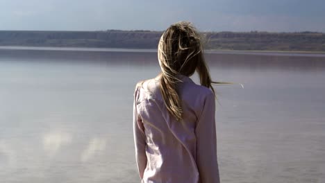 retrospectiva de una mujer de cabello largo frente al río con el viento soplando