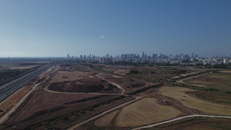 deslizamiento aéreo rápido a la derecha sobre una carretera principal, campos agrícolas y la ciudad de tel aviv en la distancia