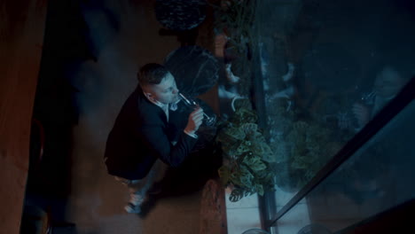man looking after plants in a cafe at night