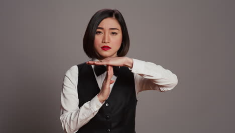 asian receptionist expressing timeout symbol on camera