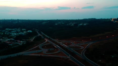 outdoor stationary drone footage at dusk of a cloverleaf traffic pattern in brasilia, brazil, with vehicles traveling home from work
