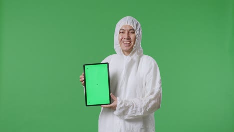 asian male scientist smiling and showing green screen tablet while standing on green screen background