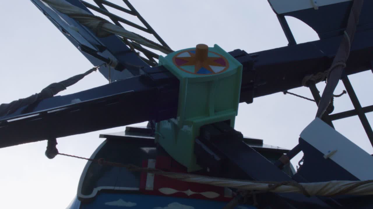 Close-up windmill blades rotate smoothly, silhouetted against cloudy daylight, upward camera angle, Zaandam