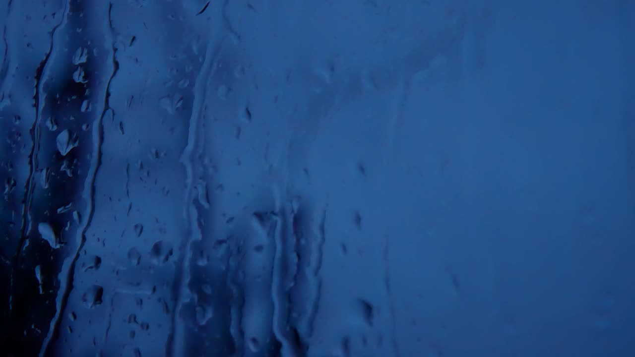 gotas de tormenta lluviosa en la noche, mal humor caen por el cristal de la ventana closeup bokeh